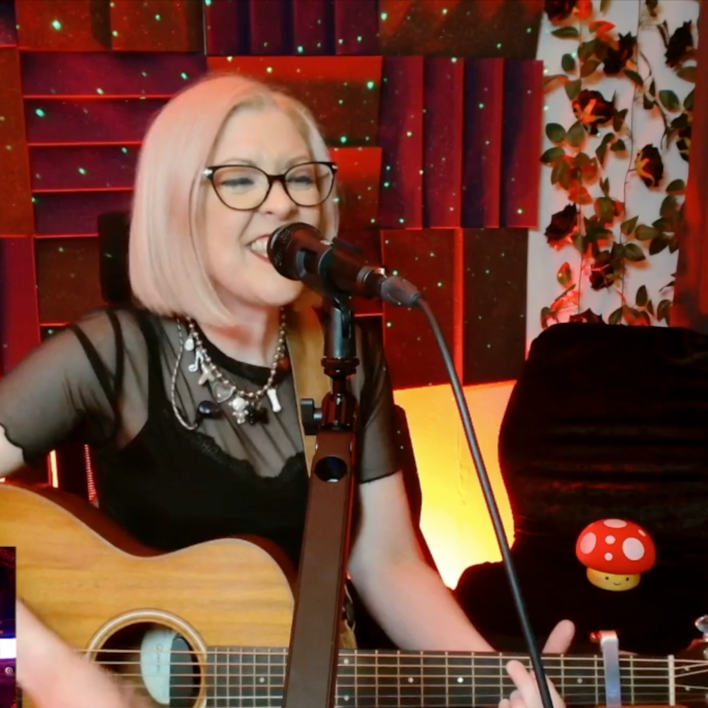 Laura is in the studio, playing acoustic guitar and singing