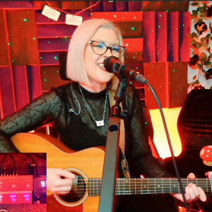 Laura is singing and playing acoustic guitar in the studio